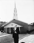 Man, presumably a minister, standing in front of First Covenant Church by Squire Haskins Photography Inc.