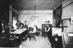 Interior of office, men sitting at work tables and desk
