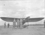 Three men standing in front of bi-wing propeller plane