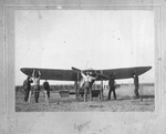 A group of men tuning up a bi-wing propeller plane in preparation for the first powered flight over Fort Worth
