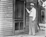 Amon G. Carter knocking on the door of an old hotel in Bowie, Texas