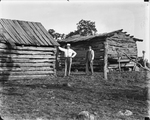 Amon G. Carter next to a log cabin in Crafton, Texas