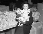 Mrs. H.A. Holtzer has an armful of dolls which will be distributed to families with children in the Goodfellows' Christmas bags, 12/21/1937