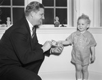 Two-year-old John Alden Farrell gives a $50 check for the Goodfellow Fund to Eddie Compton, member of Charlie Hillard's Junior Chamber of Commerce ticket selling team, 12/15/1937