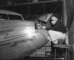 Nick Greener, relief inspector for American Air Lines, checking instruments in a giant transport plane with chief mechanic Hugh Gallemore
