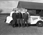 Three men standing beside automobile advertising Stock Show