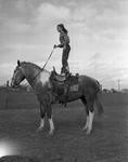 Mitzi Lucas, rodeo performer, standing on horse