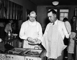 All-male church dinner at Travis Avenue Baptist Church; Dr. Paul Walthall (left), chief cook, and George Robertson assisting