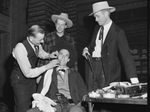 Masonic Lodge. Play cast. Dick Gaedke, left, director of the play, applying makeup for Ed. W. Hamann as A.R. Casebolt, center, standing, looks on and J. E. Kelly, right, fingers his gun