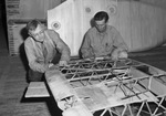 Joseph W. Kunesh, left and Ervin Luther, sanding a wrecked plane wing at the Fort Worth Bomber Plant