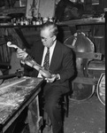 A. W. Groves looking at violin he made