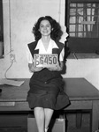 Miss Olga Thorne, deputy county tax collector, holding auto license plate