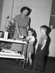 Patricia Ann Poteet, 5, and Joe Mauldin, 5, taking medicine. Mrs. Kenneth Mauldin, pouring the oil.