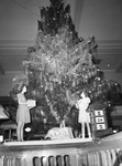 Berta Mae Beck, 13, left, and Jackie Hooe, 7, of Lena Pope Home, placing gifts on Christmas tree at First National Bank.