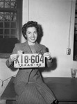 Mrs. Betty Phelan Reeder, clerk in the auto license office, shown with a license tag