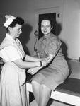 Red Cross Blood Donor Center. Captain Anne M. Smith of the Women's Air Corporation (right) blood donor, and Mrs. D. Holmes Smith, nurses aide (left)