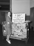 West Paper Drive: Miss Geraldine Smith surveys stack of waste paper at Montgomery Company