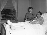 Raymond B. Jones, manager of Worth Theater, in hospital, shown buying bonds from Mrs. Willard Glazer