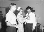 Red Cross Blood Donor Center. Supervisor C. A. Rechenthin watches Mrs. L. F. Peterson, Red Cross Gray Lady, pin silver emblem on C. L. Orrben