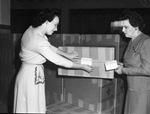 Red Cross. Christmas boxes. Mrs. Charles R. Tate (left) and Mrs. Walter Bell, placing shipment labels on boxes