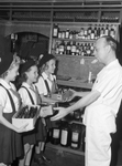 Pharmacist H. F. Hereford receiving bottles from Camp Fire Girls