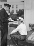 Walter Nelson, city policeman, giving ticket to loafer