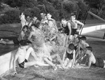 Swimming pool opening. Group of boys sprawled beneath fountain filling pool.