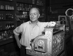 Grocer G. Brocklehurst stands beside his looted cash register