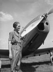 Miss Lucille Cooper, shown examining propeller of airplane.