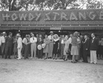 A group poses in front of a "Howdy Stranger" sign at Shady Oak Farm