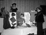 Business and Professional Women's Club. Mrs. Marie Newsom Bills, standing beside the displayed garmets. Mrs. Ruth Townsen, president of the club, is shown at the mike