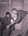 Camp Bowie, Brownwood, Texas, World War II; Texas National Guard, Private Hubert Ravey of 111th Quartermaster Regiment, has arm laceration dressed by Maj. W.E. Williams, Medical Corps