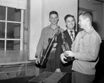 Bob McCulloch and Charles Boston show Coach Jack Harley trophies by Peggie Spencer
