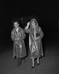 Vernon Rollins, left, and Miss Pat Mcquery, wearing raincoats
