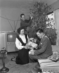 Mr. and Mrs. Joe Baldauf and her son, Corporal James L. Garvey, opening gifts beside their Christmas tree
