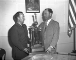 Lieutenant Colonel V. V. Laughlin, head of the city schools' Reserve Officer's Training Corp units, receiving the new city championship rifle team trophy from Amon Carter Junior