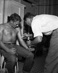 Dr. R. E. Snyder applies ointment on burns suffered by Walter Knapp