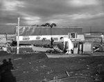 Storms. Mrs. Harold Smith inspects damage to her house trailer