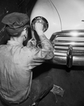 State Inspection For Automobiles. Service station attendant shown checking headlights