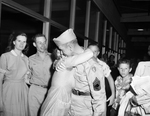 Master Sgt. Roy D. Martin being hugged by mother-in-law Mrs. Rufus Hall as Edgar Hall and Ray Martin watch by Wilburn Davis