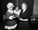 Fort Worth's Lighthouse for the Blind Christmas party; from left, Mrs. Mary Schrieber plays Mrs. Claus and Mrs. Capitola Keeter who is blind prepares packages for workers, 12/20/1954