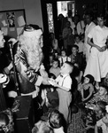 Santa Claus presents a present to Charles Maclin at the Fort Worth Crippled Children's Society party, 1508 Hemphill, 12/20/1954