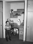Young Gary Stanley, dressed in Western clothing, stands in front of a study table in the family residence, Fort Worth, Texas
