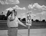 James Clark, cab driver, looking at altered sign saying 80 miles per hour, West expressway, Fort Worth, Texas