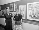 Evaline Sellors (left) and Maudie Hawkins with paintings on exhibit, Fine Arts Show, Fort Worth Public Library