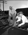 Men inspecting new rubber and asphalt pavement laid on 8th Avenue, Fort Worth, Texas