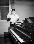 Claude Kilpatrick, 9, with player piano at Fort Worth Public Library