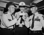 Examining a bogus $20 bill taken off one of two suspected Counterfeiter are Policeman R. M Segerstrom, Motote policeman O. E. Miller and Policeman H. T. Cluck.