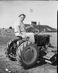 John Polzin, football coach, on tractor, helping to complete Hurst-Euless Stadium