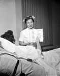 Head Nurse Betty Thweatt Holds Card for Speechless Patient
